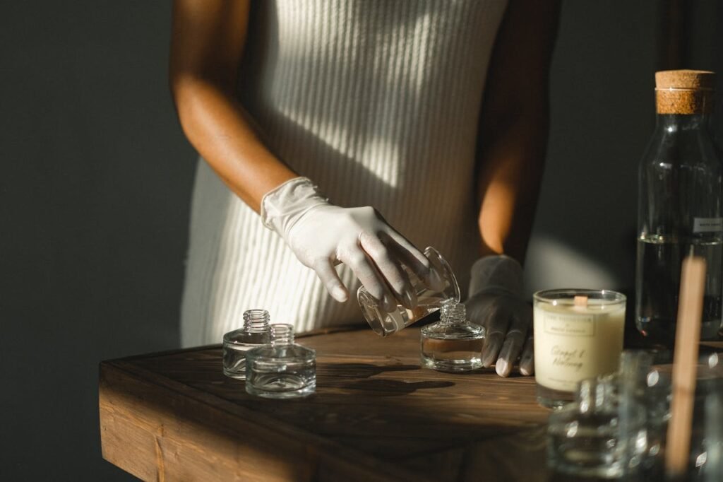 Unrecognizable crop African American female pouring essential oil in glass bottle while making liquid incense at table